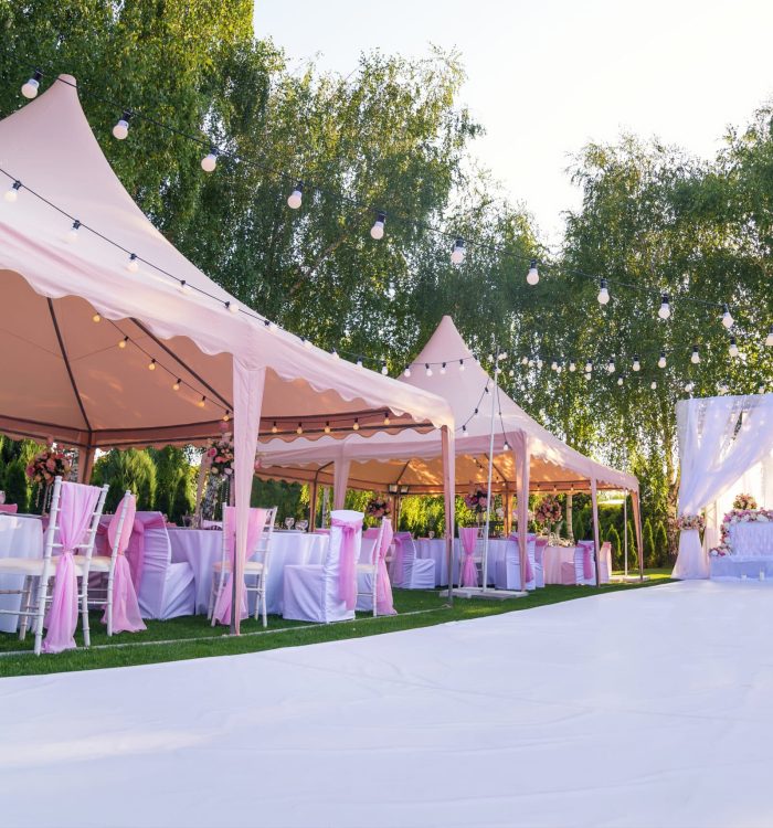 Wedding banquet outdoor in marquees on lawn decorated pink silk, lace and flowers
